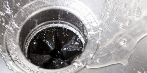 Wide shot of a garbage disposal with water running down the sink drain